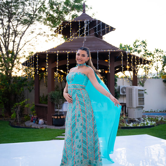 Woman in a palestinian blue henna dress standing in front of a gazebo with string lights